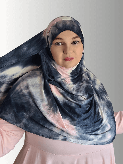 Marble hijab shawl in light pink shades mixed with dark gray colors woman gazing in the distance with a modest smile 